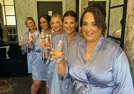 Bridesmaids in blue robes holding champagne flutes